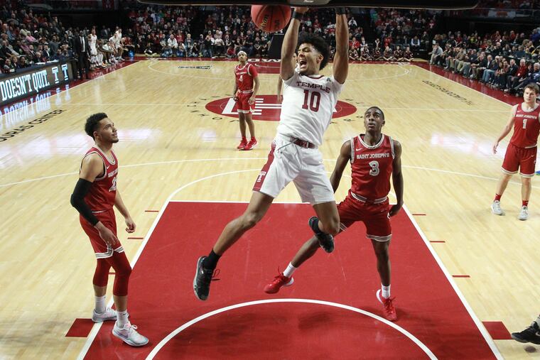 Jake Forrester, center, of Temple dunks over a Lorenzo Edwards, left, and Myles Douglas of St. Joseph’s during the 1st half on Dec. 10, 2019.