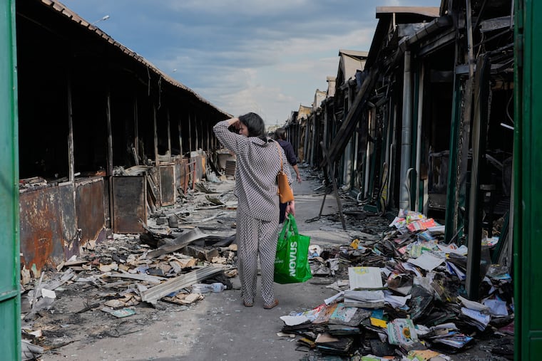 A woman reacts as she looks at charred books Wednesday after a fire at a book market in Kyiv, Ukraine that was caused by a recent Russian missile attack.