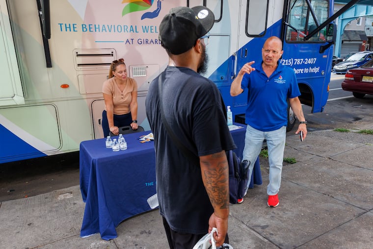 Will Rodriguez, the outreach and engagement coordinator at the Behavioral Wellness Center at Girard, speaks to a man looking to enter addiction treatment while consultant Jennifer Riley looks on. Rodriguez and a team of outreach workers regularly park on Kensington Avenue to engage people with addiction and encourage them to enter treatment. Their job has been complicated by the rise of xylazine, which causes agonizing withdrawals and painful wounds that deter many from seeking treatment.