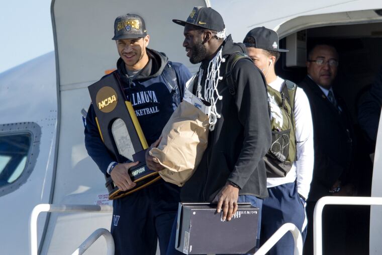 Villanova's Josh Hart holds national championship plaque as he and teammate Daniel Ochefu arrive in Philly on Tuesday.