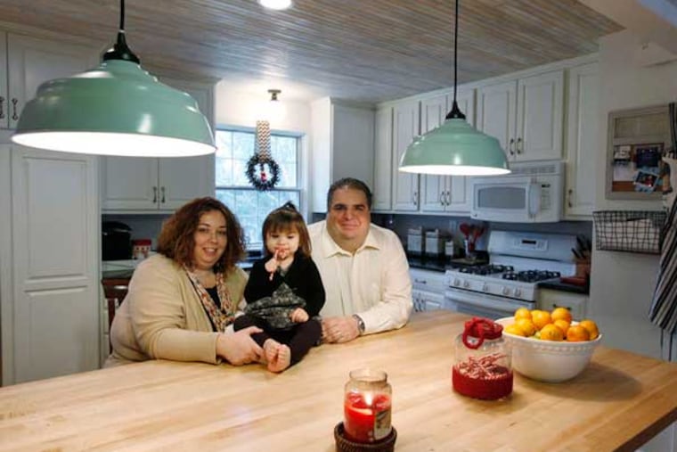 Jillian and Chris Soriano and daughter Tessa, 2, in the newly renovated kitchen of their home in Haddon Heights. They opened up a wall, added the center island, and upgraded cabinets and appliances. ( MICHAEL S. WIRTZ / Staff Photographer).