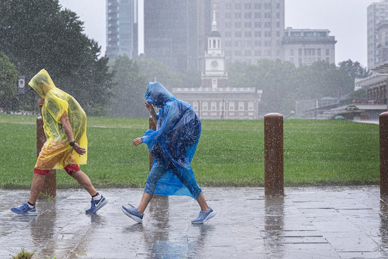 Pedestrians walk in the rain through Independence Mall during a heavy rainstorm in Philadelphia on Wednesday, Aug. 5.