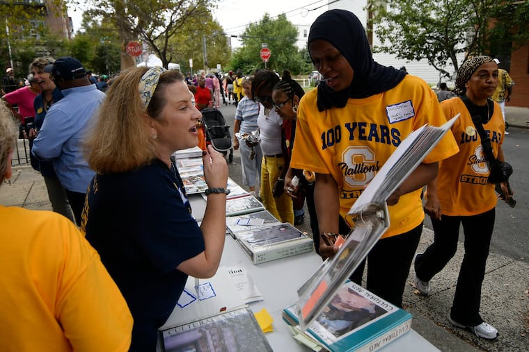 Ilene Heller, 8th grade teacher and Stanton special education assistant Dana Hill go over photo books, compiled over thirty years by retired teacher Sue Kettell (seen in the background), as students, parents, faculty, and community members gather to celebrate the centennial of the Edwin M. Stanton School with a block party at the school in Philadelphia, Pa., on Saturday, Sept. 27, 2025.