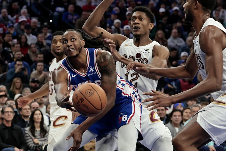 The Sixers' Jabari Walker passes the ball off as Cleveland’s De’Andre Hunter (center) defends. Hunter is a Philly native and former Friends’ Central School star.