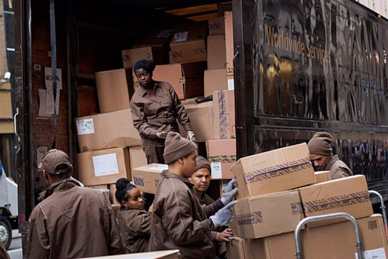 United Parcel Service Inc. (UPS) workers load boxes onto dollies for delivery in New York, U.S., on Wednesday, Nov. 12, 2014. UPS plans to spend $175 million on improving its operations during the holiday rush. It's opening 14 temporary shipping facilities to help expedite deliveries, upgrading its Orion software to plot the best route for drivers, and is hiring as many as 95,000 seasonal workers to field packages. Photographer: Michael Nagle/Bloomberg