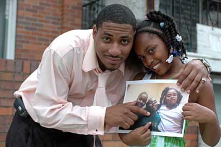 Kirtis Golden, a 28-year-old single dad, with his 9-year-old daughter Kameara outside his home. They are holding a photo and pointing to Golden's 7-year-old son Keream who he is seeking custody of. (James Heaney / Staff Photographer)