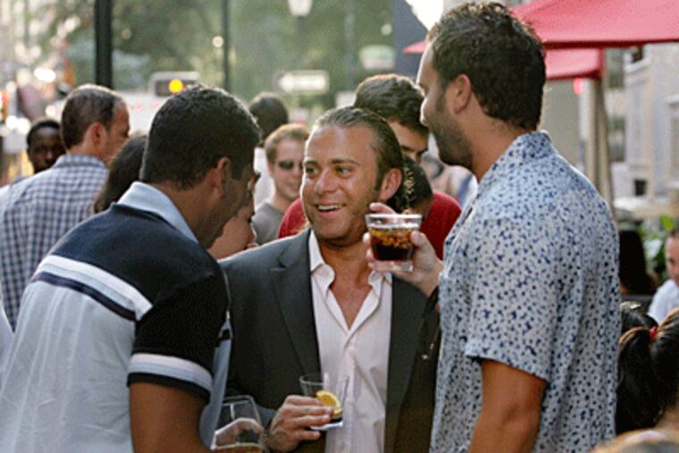 Jared Soble, 28, of Philadelphia (center) enjoys happy hour in front of Brasserie Perrier last month. (Elizabeth Robertson / Inquirer)