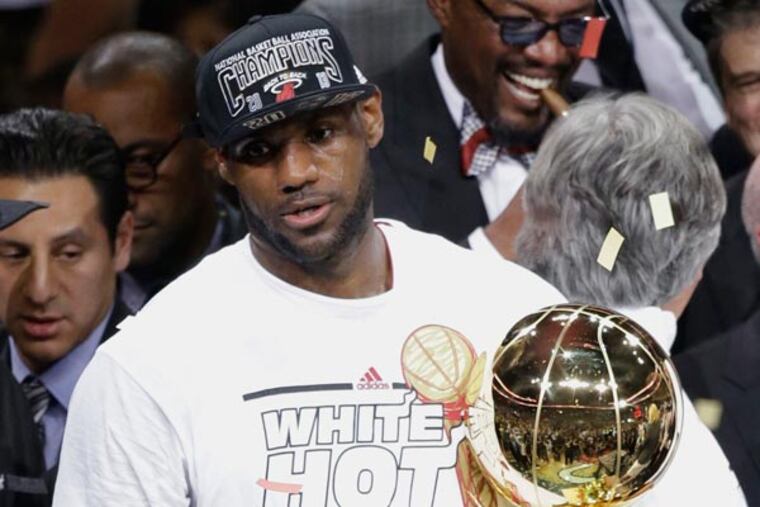 LeBron James holds the Larry O'Brien NBA Trophy after winning Game 7 of the NBA basketball championships, Friday, June 21, 2013, in Miami. The Miami Heat defeated the San Antonio Spurs 95-88 to win their second straight NBA championship. (Wilfredo Lee/AP)