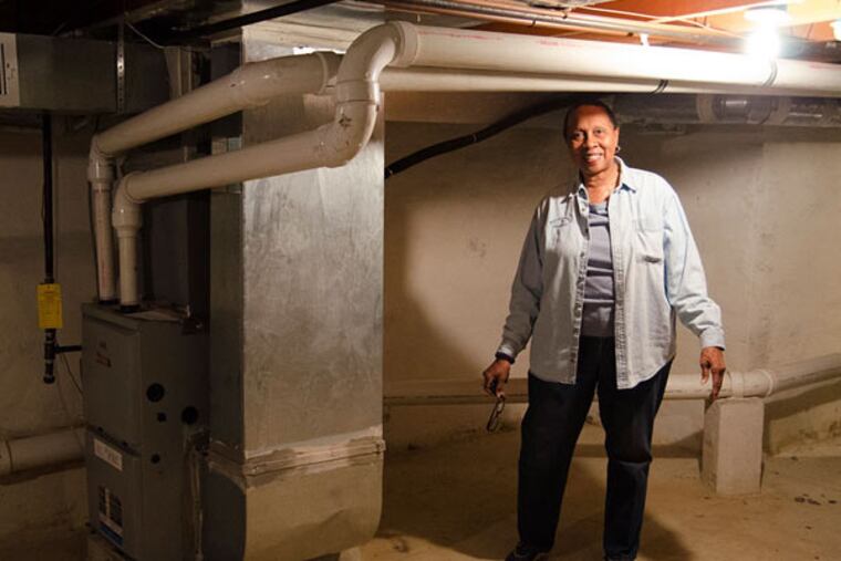 Joan Young stands beside her new furnace in her newly weatherized basement at her Mantua home. It has helped save her an estimated 30 percent in heating costs. RACHEL WISNIEWSKI / Staff Photographer