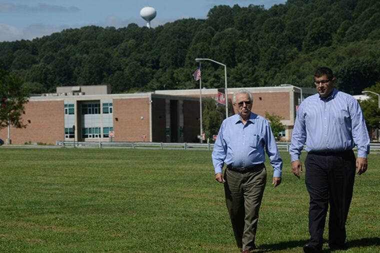 Ted Skiadas (left) and Harry "Bob" Keares of the Coatesville Solar Initiative LLC walk in a field on Coatesville Area School District High School Campus where the proposed solar installation will go. (Bob Williams/For the Inquirer)