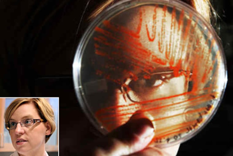 Jennifer Anthony, (also seen in inset), examines a plate of E. coli that is growing a strain of lycopene, the reddish compound in tomatoes. The lycopene resulted after she added four genes to the bacteria.