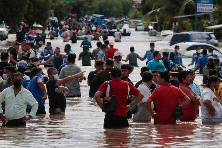 Residents wade through a flooded road in the aftermath of Hurricane Eta in Planeta, Honduras, The storm that hit Nicaragua as a Category 4 hurricane two days earlier.
