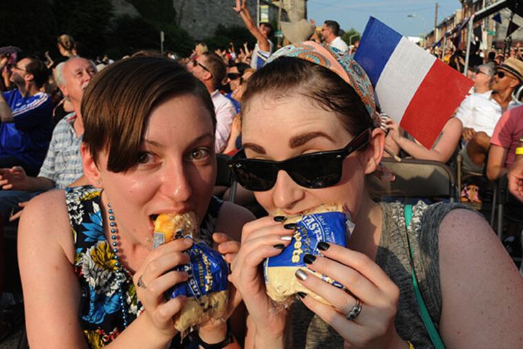 Gabriela Marcu and Michele Frederick eat Tastykake butterscotch krimpets that were tossed off the top of Eastern State Penitentiary during the 20th anniversary event commemorating Bastille Day at Eastern State Penitentiary July 13, 2014. ( CLEM MURRAY / Staff Photographer )