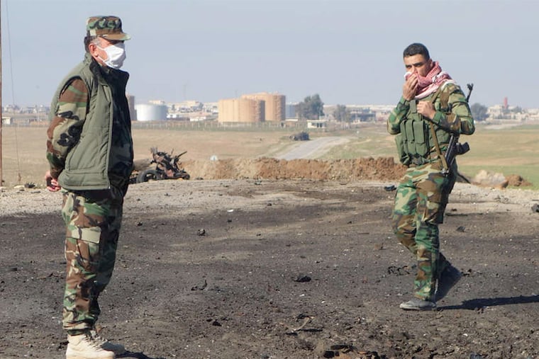 Kurdish soldiers survey the site of a bomb attack on a road between Mosul, Iraq, and the Syrian border where Kurdish authorities allege chlorine gas was used against peshmerga fighters.