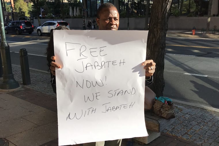 An unidentified man, one of several supporters of Mohammed Jabateh, holds a sign Tuesday outside the federal courthouse in Philadelphia. A jury is deliberating the fate of Jabateh, a Delaware County man accused of hiding his past as the Liberian warlord “Jungle Jabbah” to gain entry into the United States.