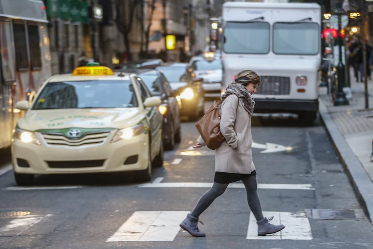 A pedestrian walks across the crosswalk at 16th and Walnut where a USPS truck blocks the turn lane on Walnut.