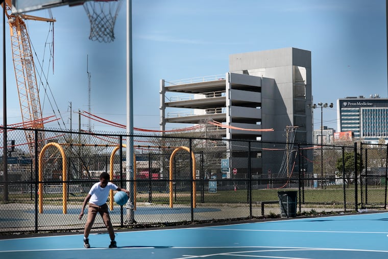 A boy plays basketball with a view of the partially collapsed garage in Grays Ferry in April. Grays Ferry is one section of the city where median household income has risen dramatically in the last decade, in part due to an influx of healthcare professionals.