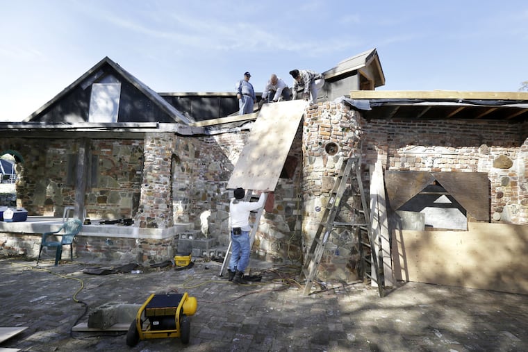 Jeffrey Triante of Vineland passes up a sheet of plywood to other volunteers putting the roof on the rebuilt/restored Palace of Depression in Vineland on October 26, 2016.