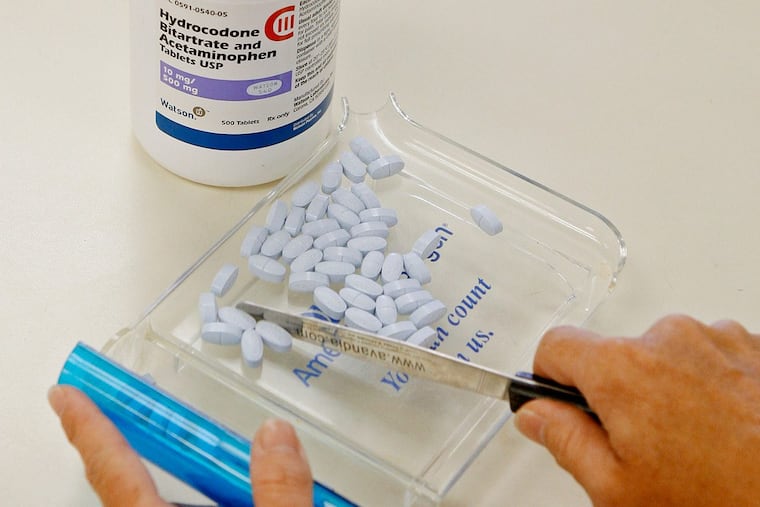 FILE – In this Aug. 5, 2010 file photo, a pharmacy tech poses for a picture with hydrocodone bitartrate and acetaminophen tablets, the generic version of Vicodin in Edmond, Okla.