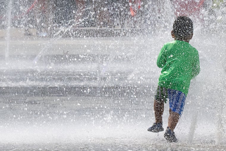 A young boy runs through the spray from the fountains at Love Park on Wednesday.