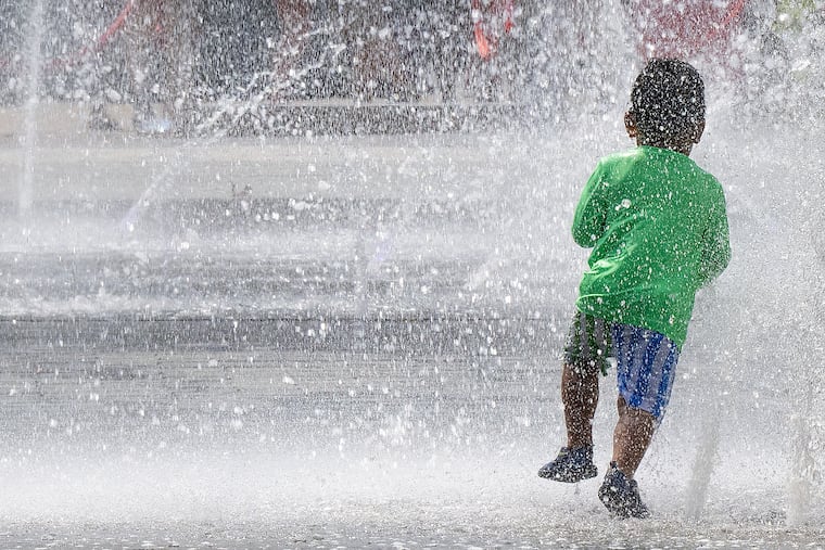 A young boy runs through the spray from the fountains at LOVE Park on a hot summer day on July 1. Temperatures are expected to break a bit Saturday into Sunday as the heat wave finally moves out of the region.
