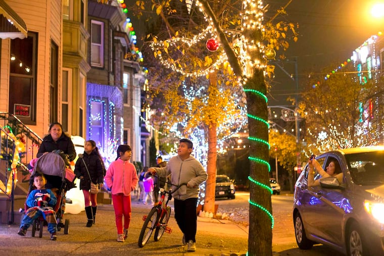 Magdalena Vazquez walks with her children through the 1600 block of South 13th Street Friday, November 25, 2016, where thousands of lights are being put up for the "Miracle on South 13th Street."