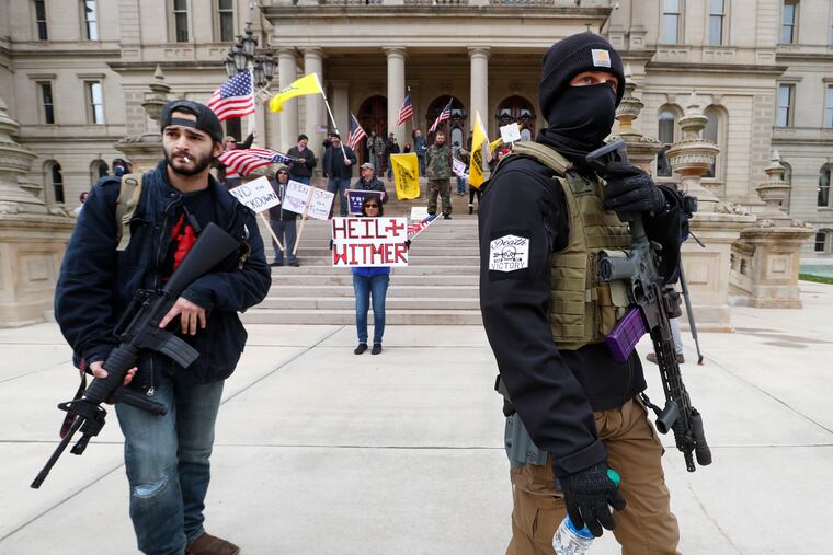 Protesters carry rifles near the steps of the Michigan State Capitol building in Lansing, Mich., in April.