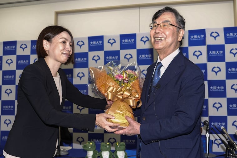 Osaka University professor Dr. Shimon Sakaguchi, right, receives flowers after winning the Nobel Prize in medicine on Monday, Oct. 6.