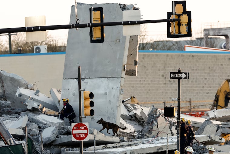 Firefighters and Pennsylvania Urban Search and Rescue look through the site of the partial parking garage collapse in Grays Ferry on Sunday, April 12, 2026, in Philadelphia.