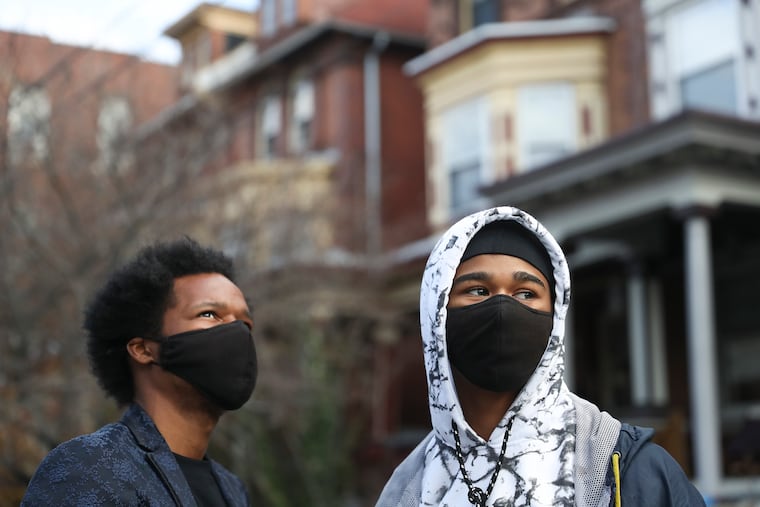 Brothers Mark Holly, left, and Elijah Johnson pose for a portrait on the street of their new home in West Philadelphia on Tuesday, Dec. 22, 2020. Elijah and Mark lived in Mark's rental car for a year, even while Mark was enrolled at CCP and Elijah struggled through high school. They got a place to live after Elijah won an essay contest and his school, Achievement House Cyber Charter, rallied around him. The mayor's office intervened and now the brothers have a home, just in time for Christmas.