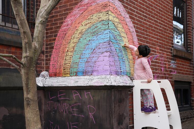 Four-year-old Juniper Assis Finlayson colors in blank spots with chalk on a rainbow she and her Mom drew earlier in the week on Tuesday, in Philadelphia, March 27, 2020. Juniper also enjoys going for walks with her mom's and participating in the rainbow scavenger hunt around 26th and Poplar Streets.