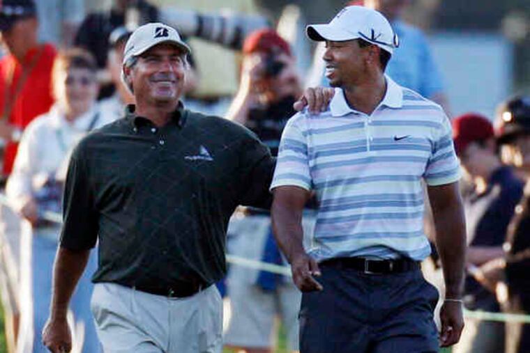 During a Masters practice round, Fred Couples and Tiger Woods share a laugh walking down the fairway after teeing off.