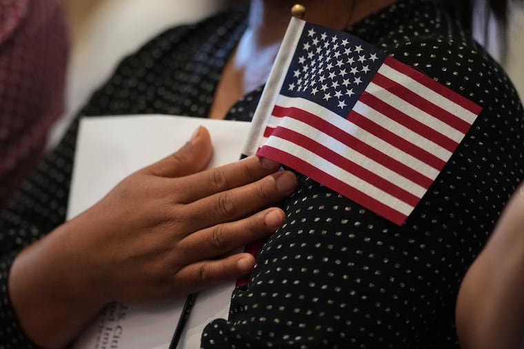 A woman clutches a U.S. flag as she and applicants from other countries prepare to take the Oath of Citizenship in commemoration of Independence Day during a naturalization ceremony in San Antonio on July 3, 2025.