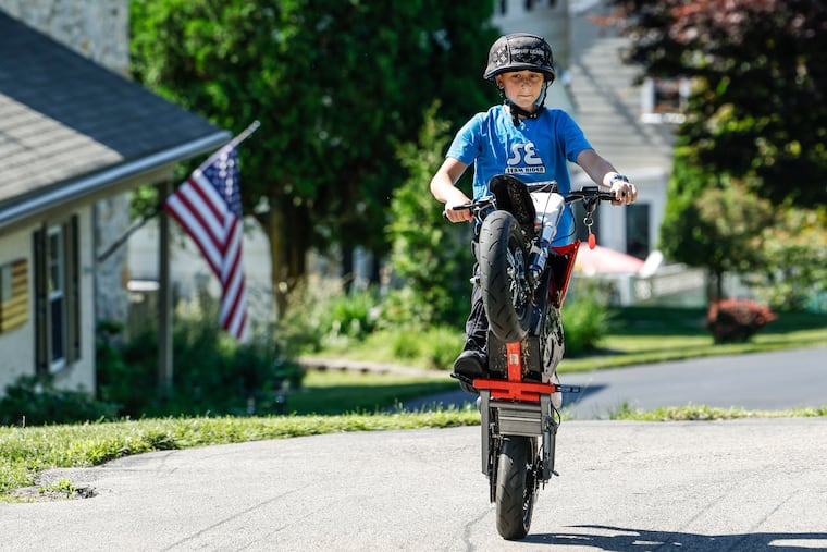 Oneway Lilman, 11, in his custom-made Louis Vuitton helmet, doing a wheelie on an electric-powered Razor Dirt Rocket in the driveway of his suburban home.