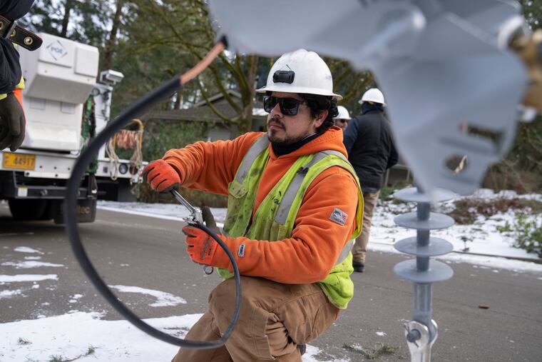 A worker from Portland General Electric replaces a power line as crews work to restore power in Lake Oswego, Ore., last month.