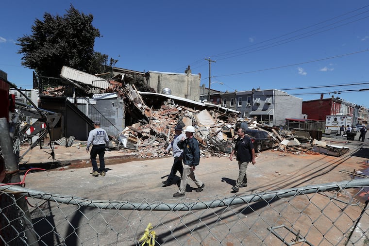 Investigators examine the remains of the collapsed three-story building along the 300 block of West Indiana Avenue in the Fairhill section of Philadelphia on Sunday, one day after a firefighter died and four others, along with a city building inspector, were injured in the post-fire collapse.