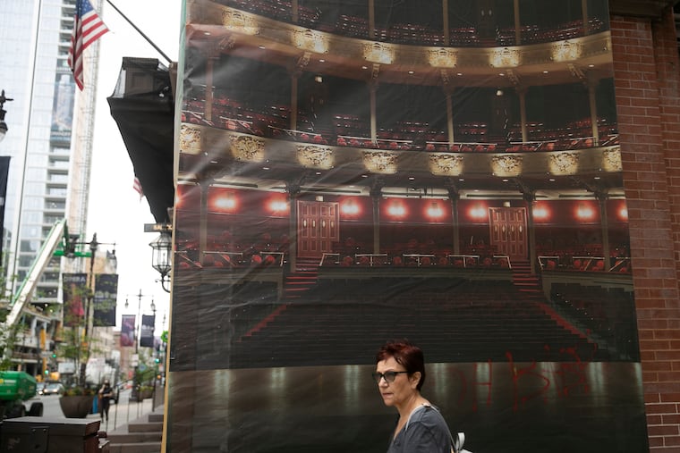 A pedestrian walks past a poster of the opera outside of the Kimmel Center Thursday at Philly's Avenue of the Arts.