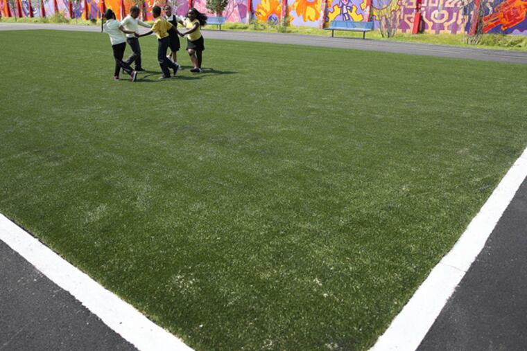 Students from the William Dick School play on the new artificial turf field on the school's playground in North Philadelphia on June 3, 2014. (DAVID MAIALETTI / Staff Photographer)