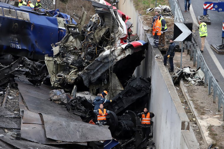 Workers supported by a crane try to remove debris from the rail lines after a collision in Tempe, about 376 kilometres (235 miles) north of Athens, near Larissa city, Greece, on Thursday.