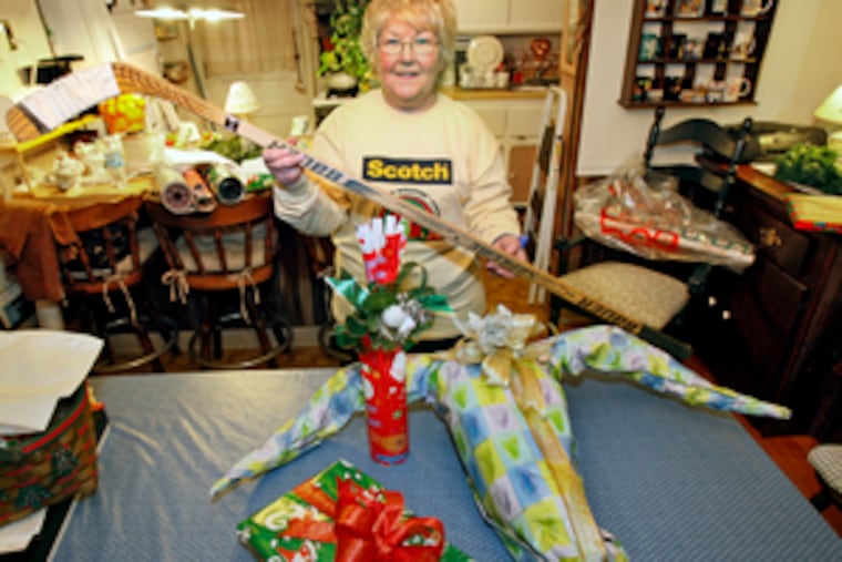Janet Smith with several finished gifts and a hockey stick. To disguise it, she needed - but didn't have - cardboard. "Frankly, I don't think it's always important to disguise a gift," says the expert gift wrapper.