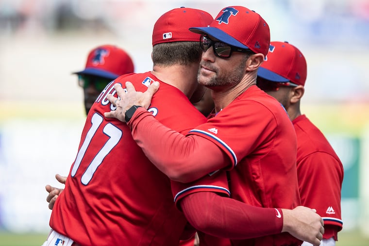 Gabe Kapler, right, hugs Rhys Hoskins before a spring-training game at Spectrum Field.