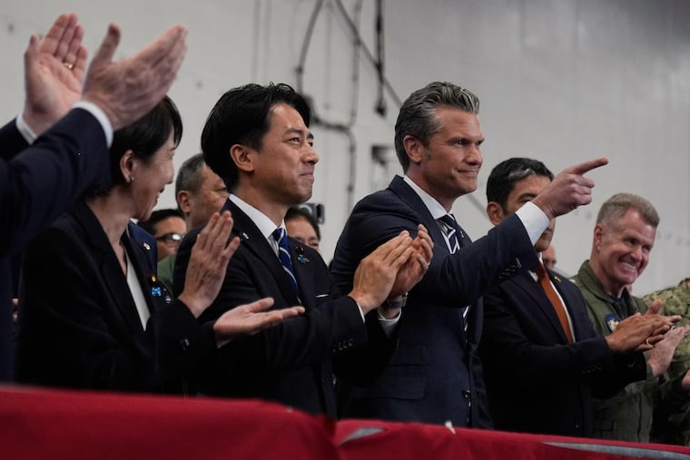 U.S. Defense Secretary Pete Hegseth (center right), with Japanese Prime Minister Sanae Takaichi (left) and Defense Minister Shinjiro Koizumi, gestures as they listen to President Donald Trump speak to members of the military aboard the USS George Washington in Yokosuka, south of Tokyo, on Tuesday, Oct. 28.