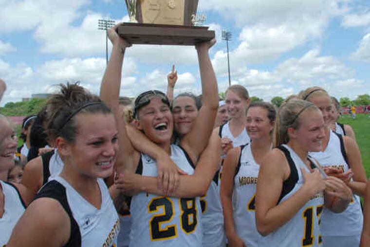 Moorestown's Alyssa Ogle holds the championship trophy while getting a hug from Nicole Laitner. Jenna Hildeband is at left, and Haleigh Dalmass and Katrina Martinelli (17) are right.