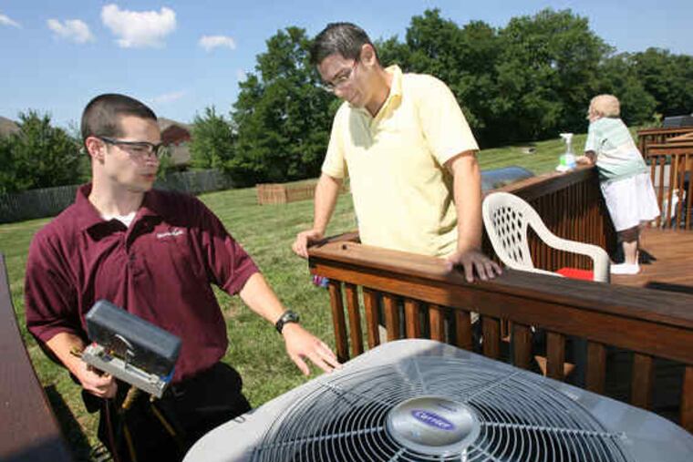 Josh Pierce (left) a service manager with ServiceMark, talks with homeowner Chad Vanning of Limerick about a recently installed high-efficiency central air-conditioning system.