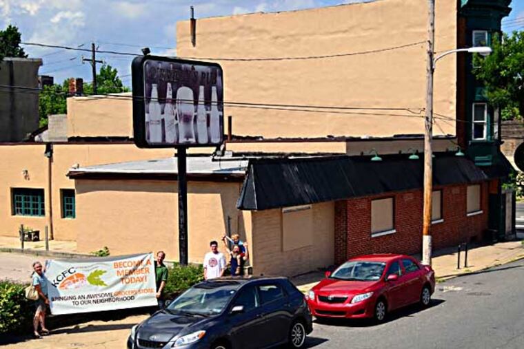 Kensington Community Food Co-op president Lena Helen (left) and board member Jeff Carpineta, hold the banner that will be hanging in their first official store located on the corner of Lehigh Ave. and Coral St. on Friday, June 27, 2014. C.F. Sanchez / Staff Photographer