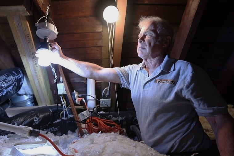 Bill Earl adjusts one of two strobe lights that deter squirrels in the attic in the home of Julie Cottage in West Chester Thursday May 10, 2018.