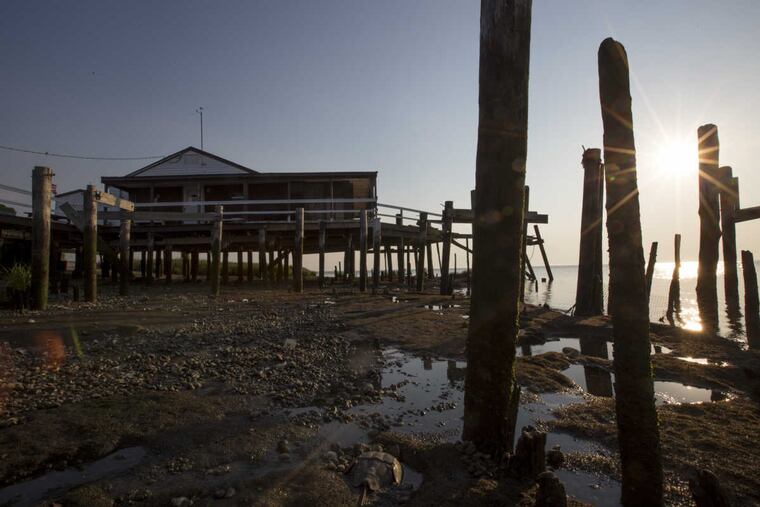 The sun sets on an abandoned home where voices are heard inside on Money Island Tuesday, June 13, 2017. Downe Township, NJ, faces affects of sea rise, and the state is buying homes to move people out before a rising tide does it for them.