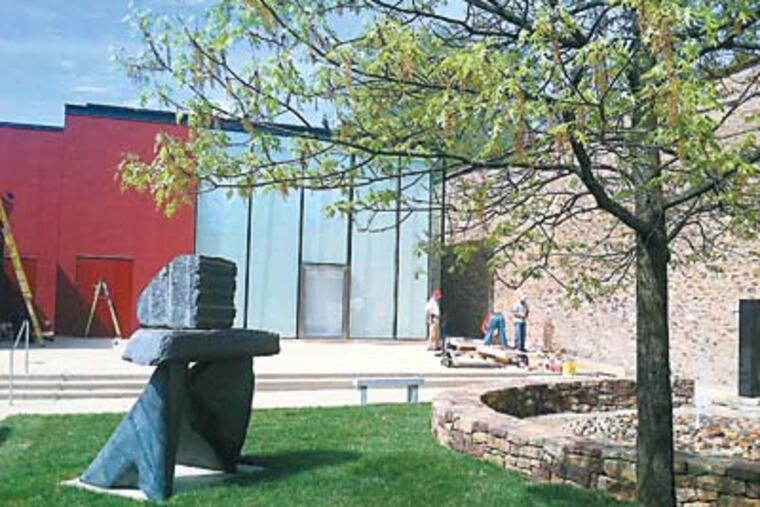 Workers install benches in the Patricia D. Pfundt Sculpture Garden on Tuesday, in time for the dedication of the glass Edgar N. Putman Event Pavilion (center) on Wednesday. (Bill Reed/Staff)