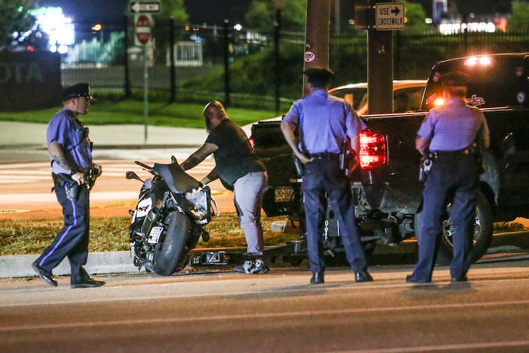 Police watch as a tow truck operator picks up a motorcycle that off-duty police officer Thomas Munz was riding when he was involved in a fatal crash on Tuesday night.