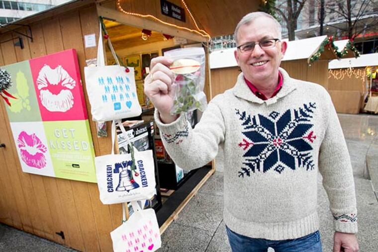 James McManaman, owner of Absolute Abstract at his booth in the Christmas Village, in LOVE Park in center city on Friday, December 6, 2013. James is holding a small packet of Mistletoe he sells. ( ALEJANDRO A. ALVAREZ / STAFF PHOTOGRAPHER )